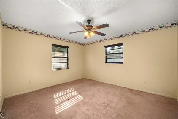 a view of a big room with windows and chandelier fan
