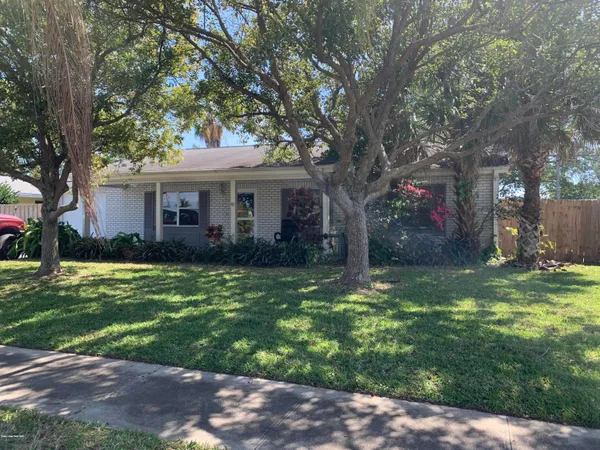 a backyard of a house with table and chairs plants and large trees