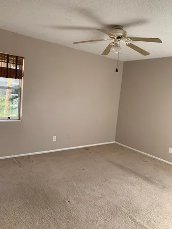an empty room with a window and a fan