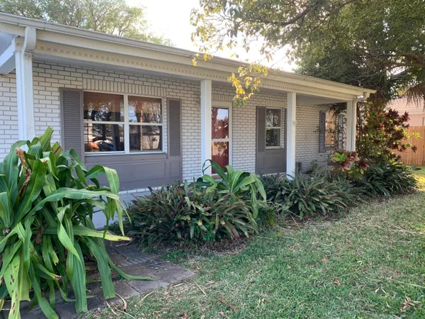 a view of a house with potted plants and a table and chairs