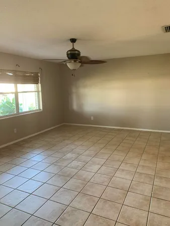 an empty room with windows and ceiling fan