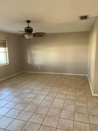 an empty room with a ceiling fan and window