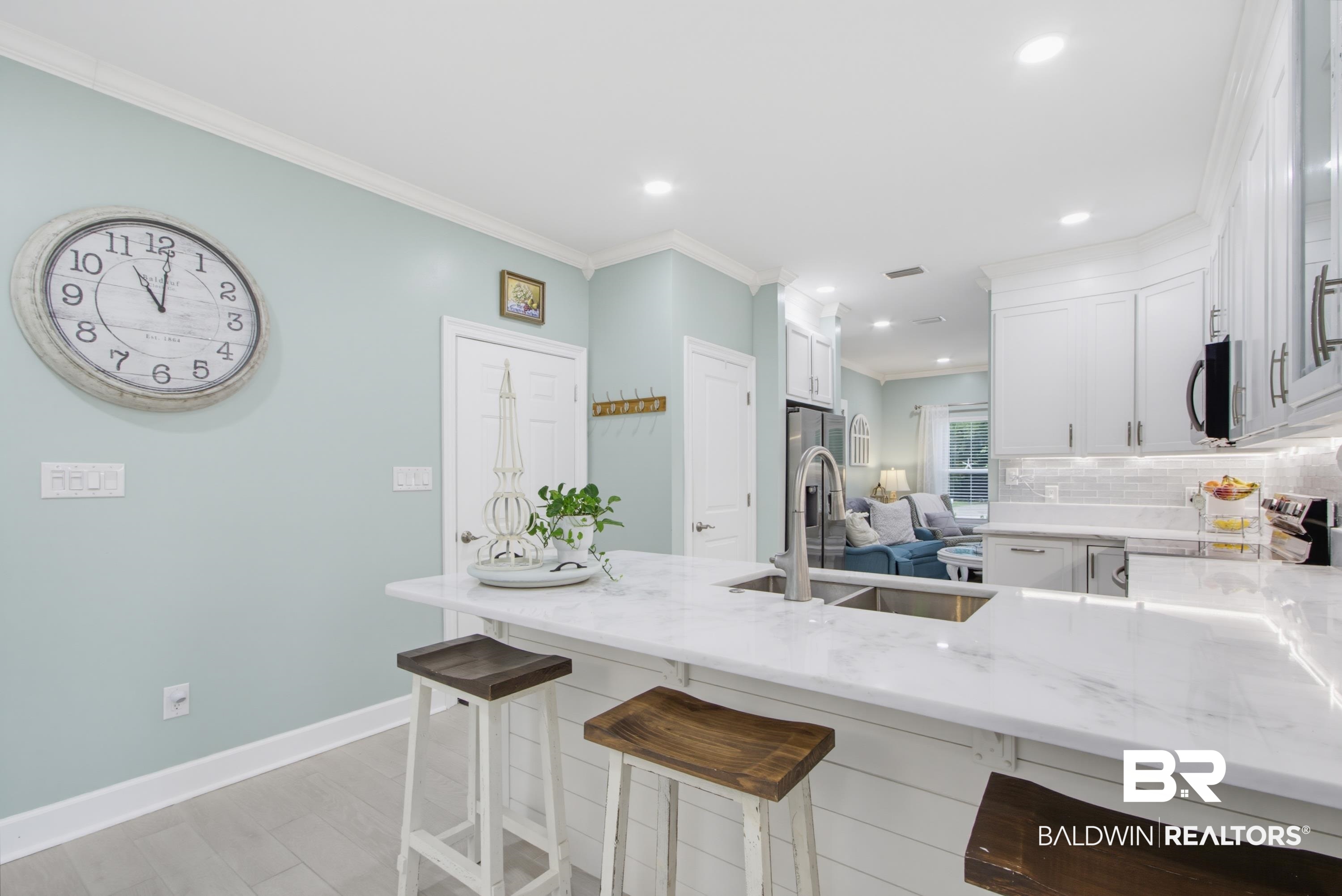 7472 Coopers Landing Road Foley, AL 36535 - Photo 11 of 40 Kitchen island featuring a dual-basin stainless steel sink with a high-arc faucet, complemented by white cabinetry, light-toned flooring, and recessed lighting