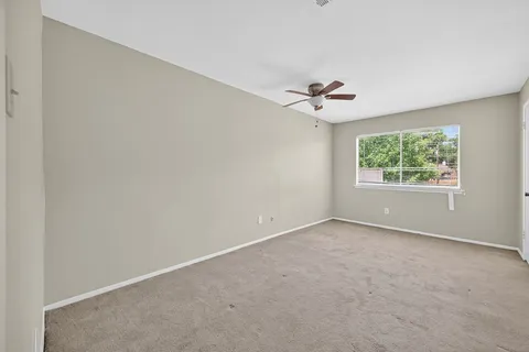 an empty room with windows and chandelier fan