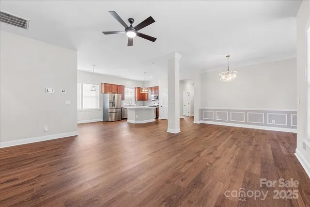 an empty room with wooden floor and a ceiling fan
