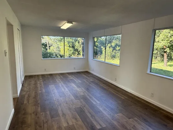 a view of an empty room with wooden floor and a window