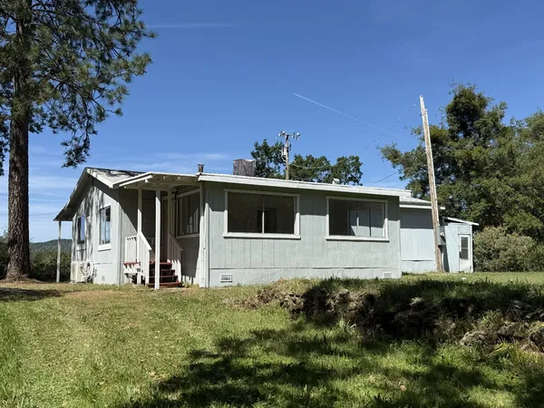 a front view of house with yard and trees in the background