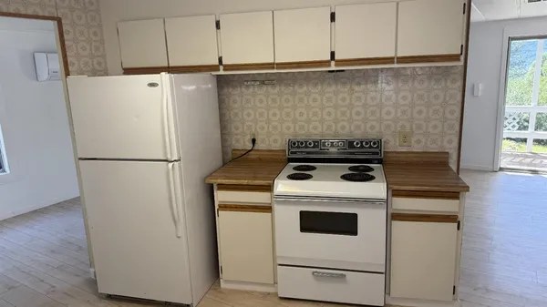 a white refrigerator freezer and a stove sitting inside of a kitchen