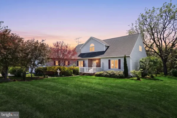 a front view of a house with a garden and trees