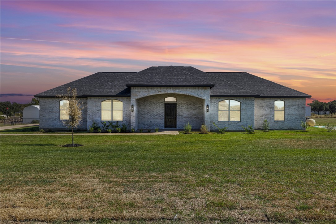 French country style house featuring brick siding, a front yard, and roof with shingles