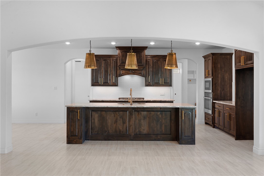 6524 Agave Court Bryan, TX 77808 - Photo 13 of 43 Kitchen featuring arched walkways, dark brown cabinets, pendant lighting, and recessed lighting