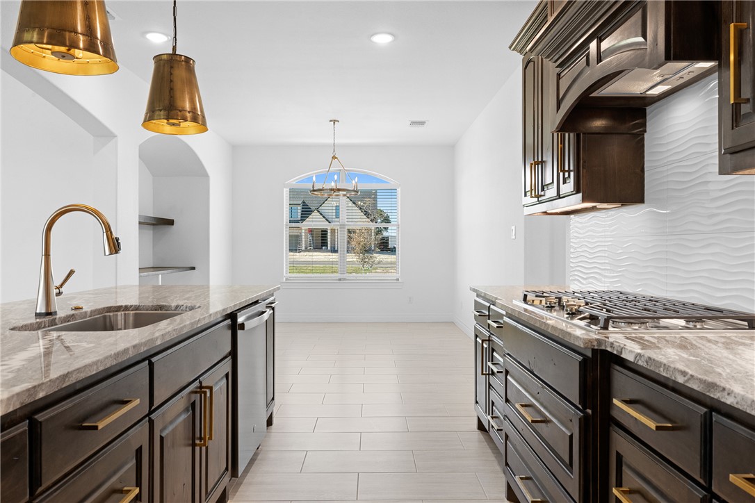 6524 Agave Court Bryan, TX 77808 - Photo 19 of 43 Kitchen featuring dark brown cabinetry, light stone countertops, recessed lighting, hanging light fixtures, and decorative backsplash