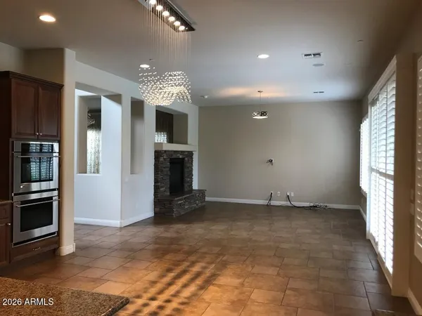 a view of an empty room with kitchen and a window