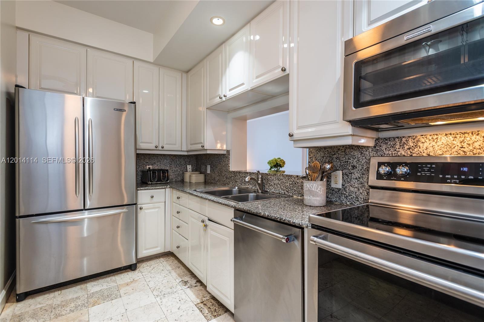 888 Brickell Key Drive, Unit 211 Miami, FL 33131 - Photo 9 of 28 a kitchen with stainless steel appliances granite countertop a refrigerator microwave and sink