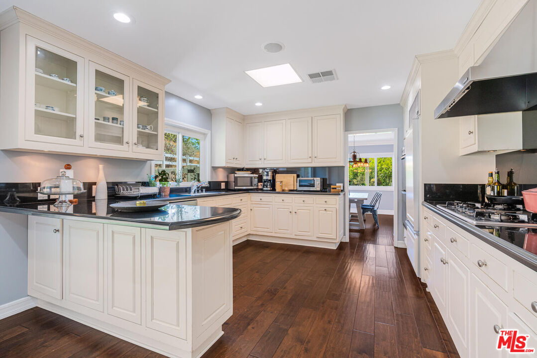 24975 Kit Carson Road Hidden Hills, CA 91302 - Photo 14 of 38 a kitchen with stainless steel appliances granite countertop a stove a sink a refrigerator and white cabinets with wooden floor