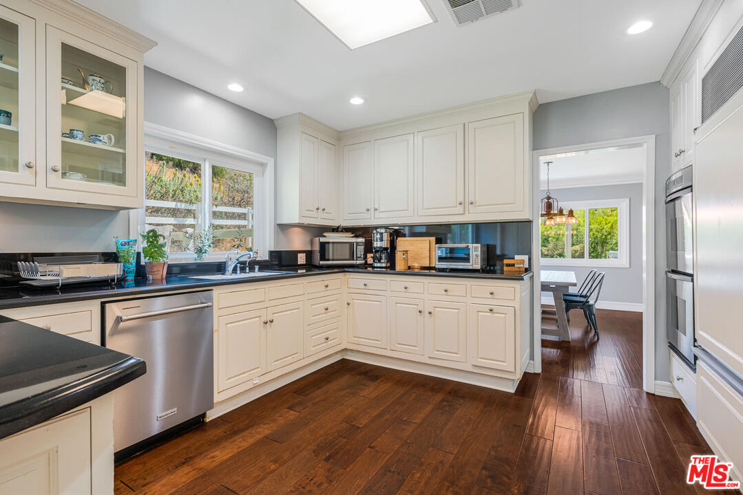 24975 Kit Carson Road Hidden Hills, CA 91302 - Photo 16 of 38 a kitchen with a white cabinets and black stainless steel appliances