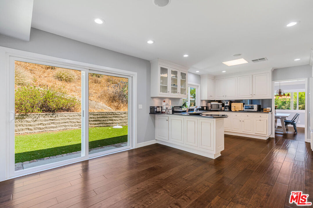 24975 Kit Carson Road Hidden Hills, CA 91302 - Photo 17 of 38 a kitchen with sink and white cabinets with wooden floor