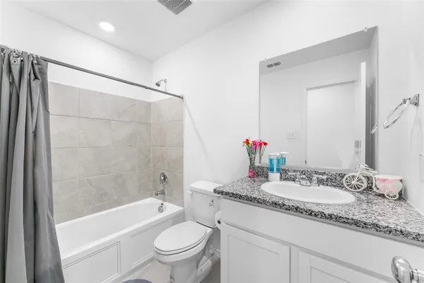 a bathroom with a granite countertop sink a toilet and shower
