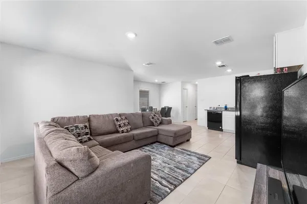 a living room with furniture and a refrigerator