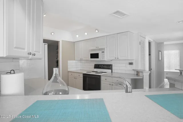 a kitchen with stainless steel appliances kitchen island granite countertop a refrigerator oven a sink dishwasher and white cabinets with wooden floor