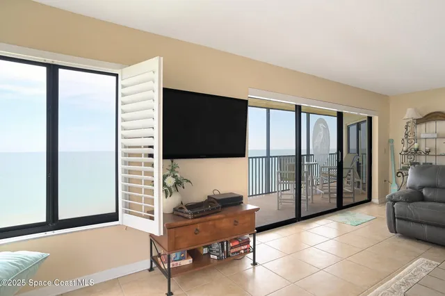 a living room with furniture a flat screen tv and a floor to ceiling window