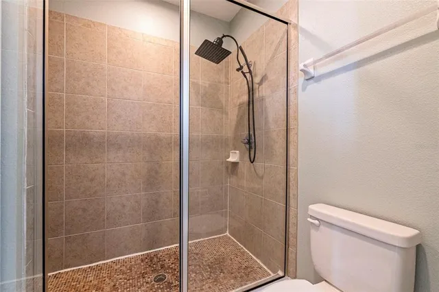 a bathroom with a shower a toilet and a window