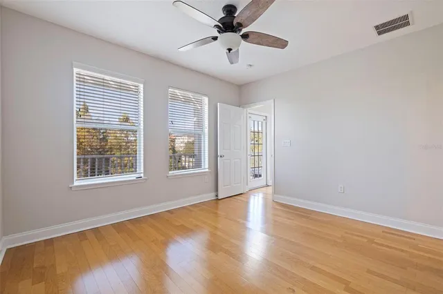 a view of an empty room with a window and wooden floor