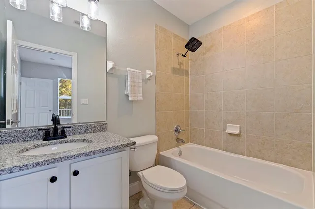 a bathroom with a granite countertop toilet a sink and a bathtub