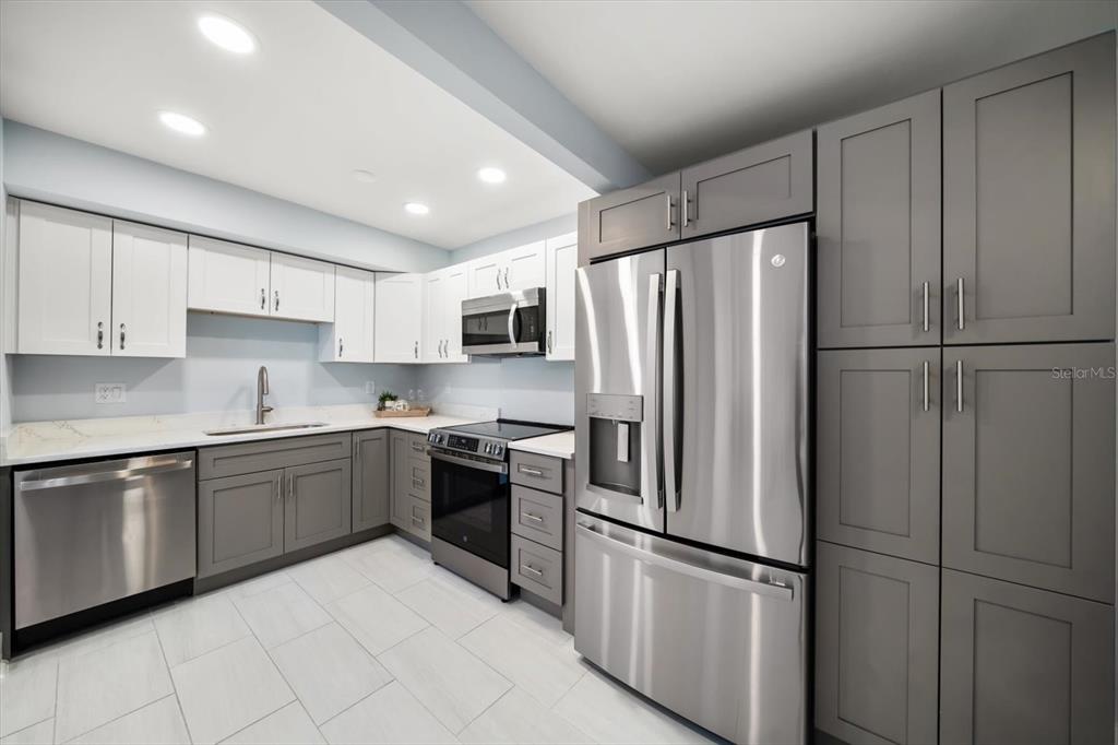 1 Windrush Boulevard, Unit 45 Indian Rocks Beach, FL 33785 - Photo 12 of 53 a kitchen with stainless steel appliances granite countertop a refrigerator sink and cabinets