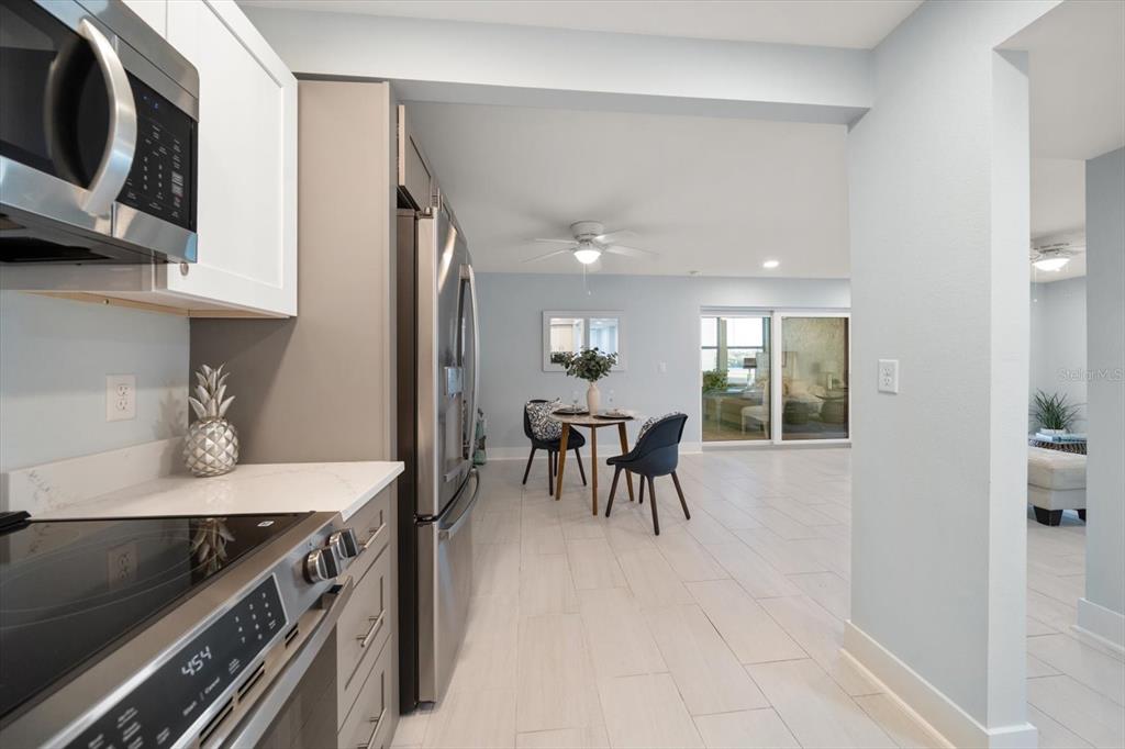 1 Windrush Boulevard, Unit 45 Indian Rocks Beach, FL 33785 - Photo 15 of 53 a kitchen with stainless steel appliances granite countertop a stove top oven a sink a dining table and chairs with wooden floor