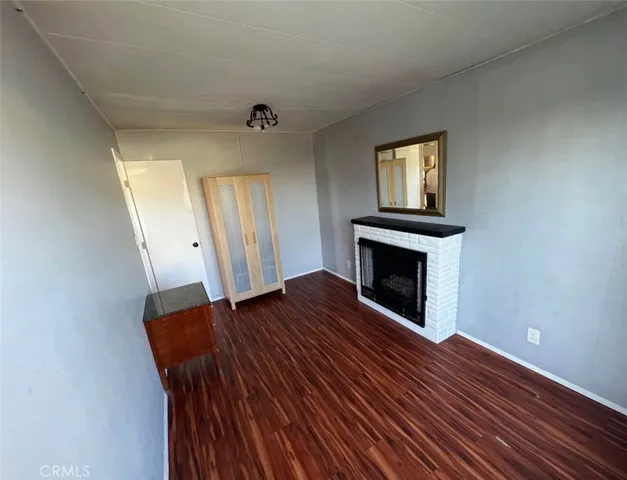 an empty room with wooden floor fireplace and windows