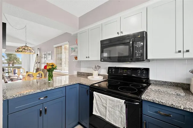 a kitchen with granite countertop a sink a stove and cabinets