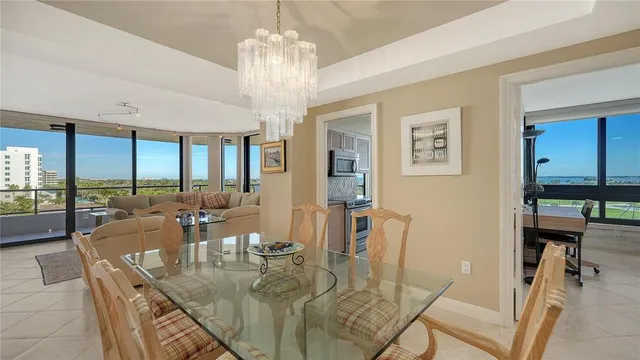 a view of a dining room with furniture a chandelier and large windows