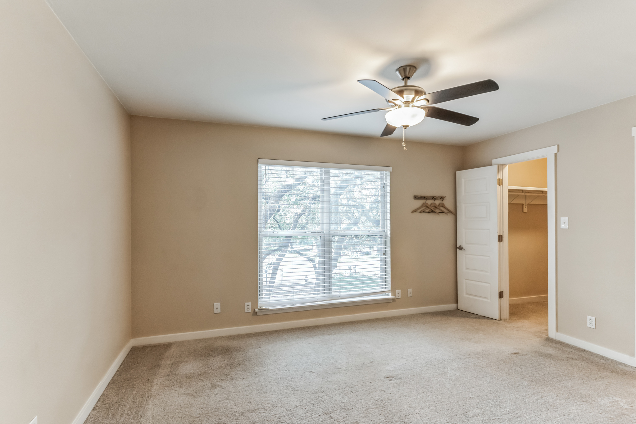 3214 Clawson Road, Unit A Austin, TX 78704 - Photo 11 of 26 A quiet bedroom offers serene outdoor views through a large window, complemented by a practical ceiling fan for comfort.