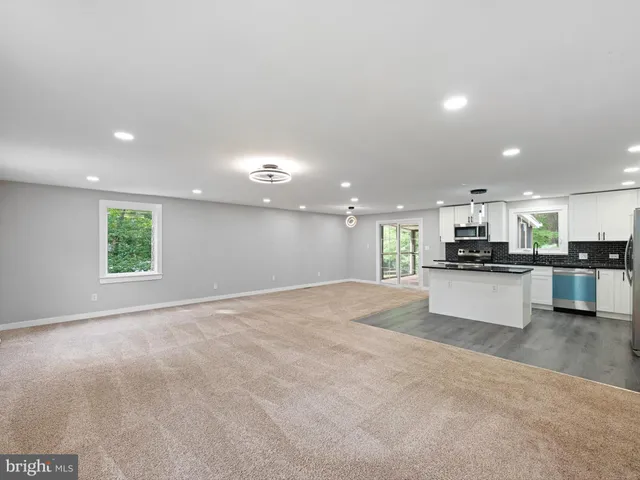 a view of kitchen with kitchen island a counter top space a sink stainless steel appliances and cabinets