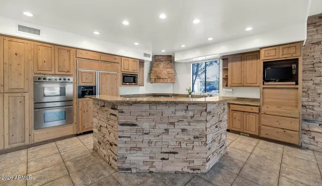 a kitchen with stainless steel appliances kitchen island granite countertop a refrigerator and a stove top oven