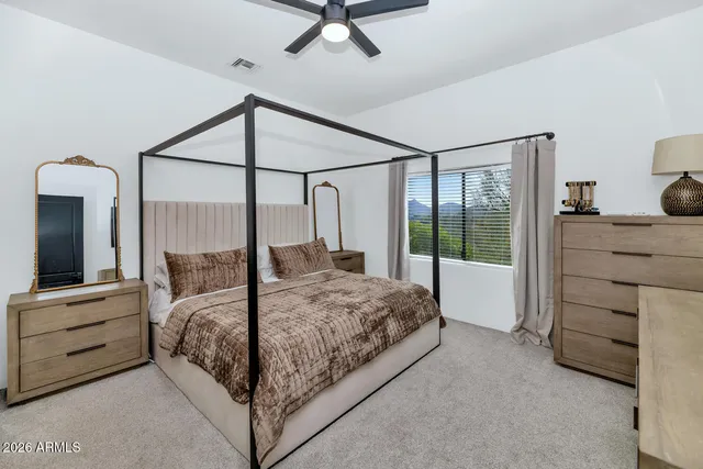 a bedroom with a large bed and a chandelier fan