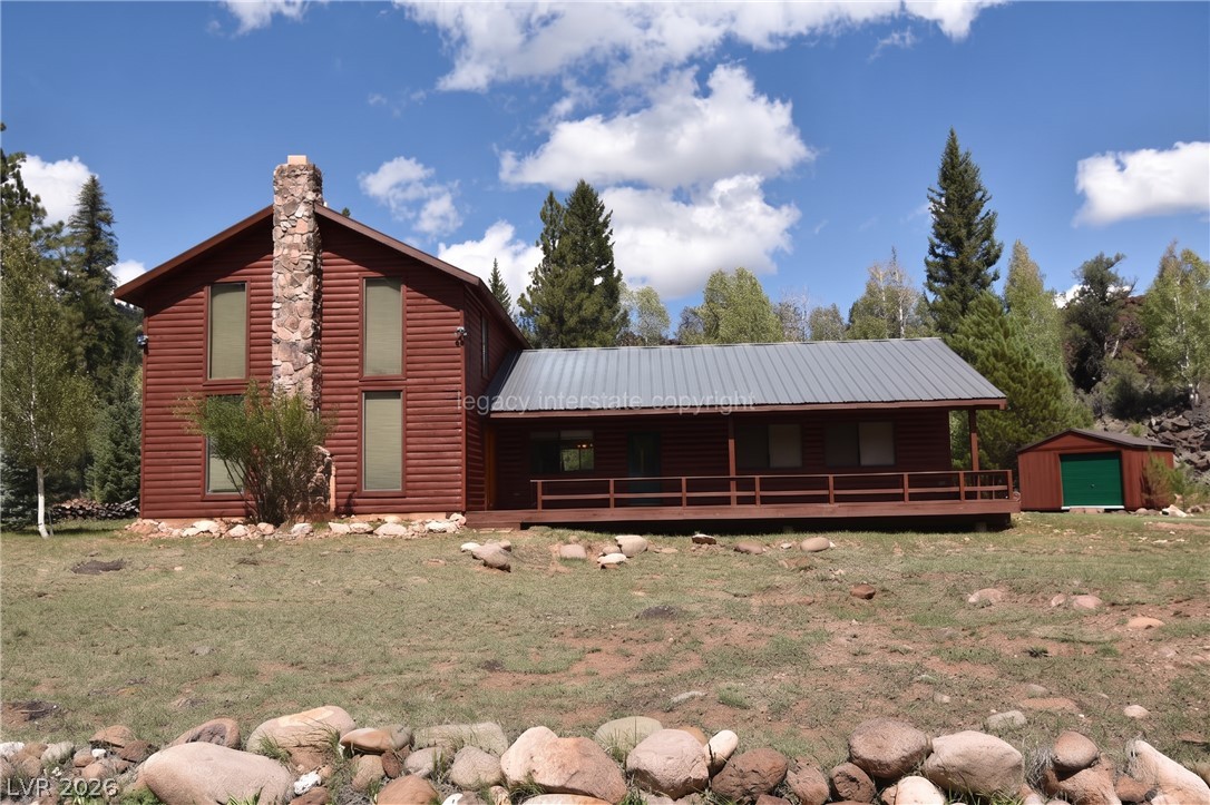 1129 East Ponderosa Road Hatch, UT 84735 - Photo 42 of 47 Wood siding and a prominent stone chimney define this mountain home under a metal roof.