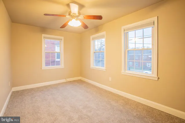 an empty room with windows and fan