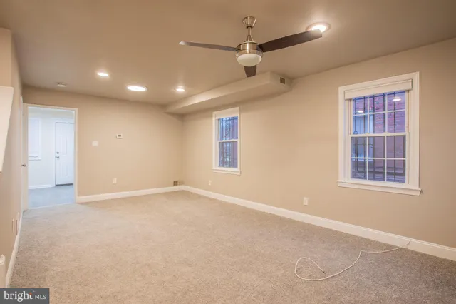 an empty room with windows and fan