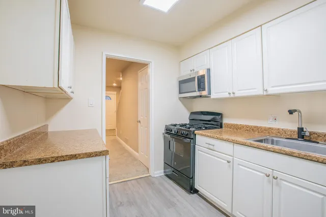 a kitchen with granite countertop a sink stove and cabinets
