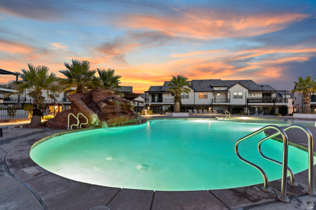2600 Ocotillo Way, Unit 31 Santa Clara, UT 84765 - Photo 52 of 73 Curved swimming pool featuring a rock waterfall, mature palm trees, and perimeter concrete decking