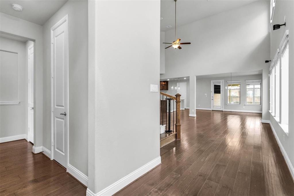 6333 Hall Road Frisco, TX 75034 - Photo 6 of 38 Expansive living area featuring soaring ceilings, wood-finish flooring, multiple windows, a ceiling fan, and a staircase with wood and metal railing