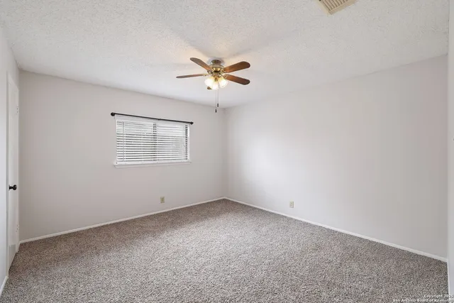 a view of an empty room with a ceiling fan and a window