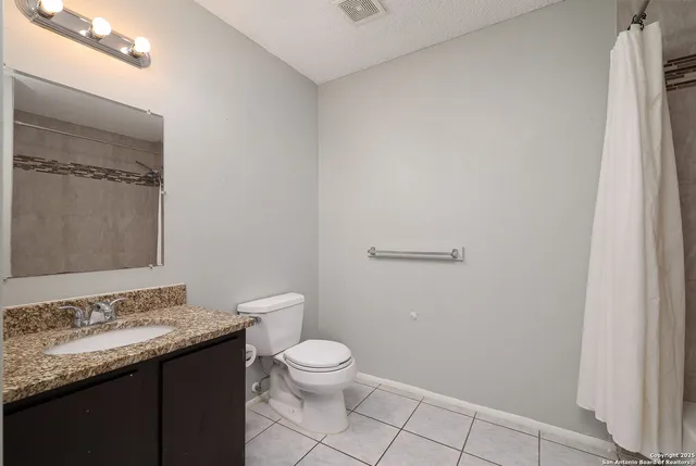 a bathroom with a granite countertop sink a toilet and a mirror