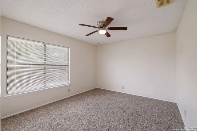 an empty room with a window and a fan