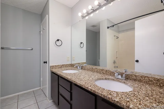 a bathroom with a granite countertop sink and a mirror