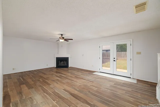 wooden floor fireplace and windows in an empty room