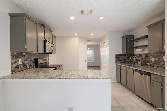 a kitchen with stainless steel appliances granite countertop a sink stove and cabinets