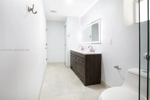 a bathroom with a double vanity sink mirror and toilet
